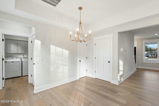 unfurnished dining area featuring washer and dryer, light wood-type flooring, and a chandelier