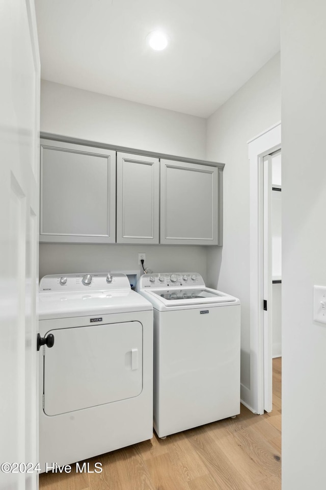 washroom with cabinets, independent washer and dryer, and light wood-type flooring