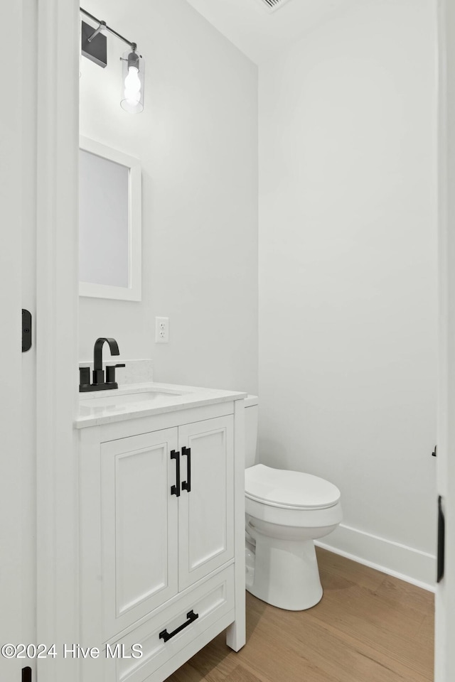 bathroom featuring toilet, vanity, and hardwood / wood-style flooring