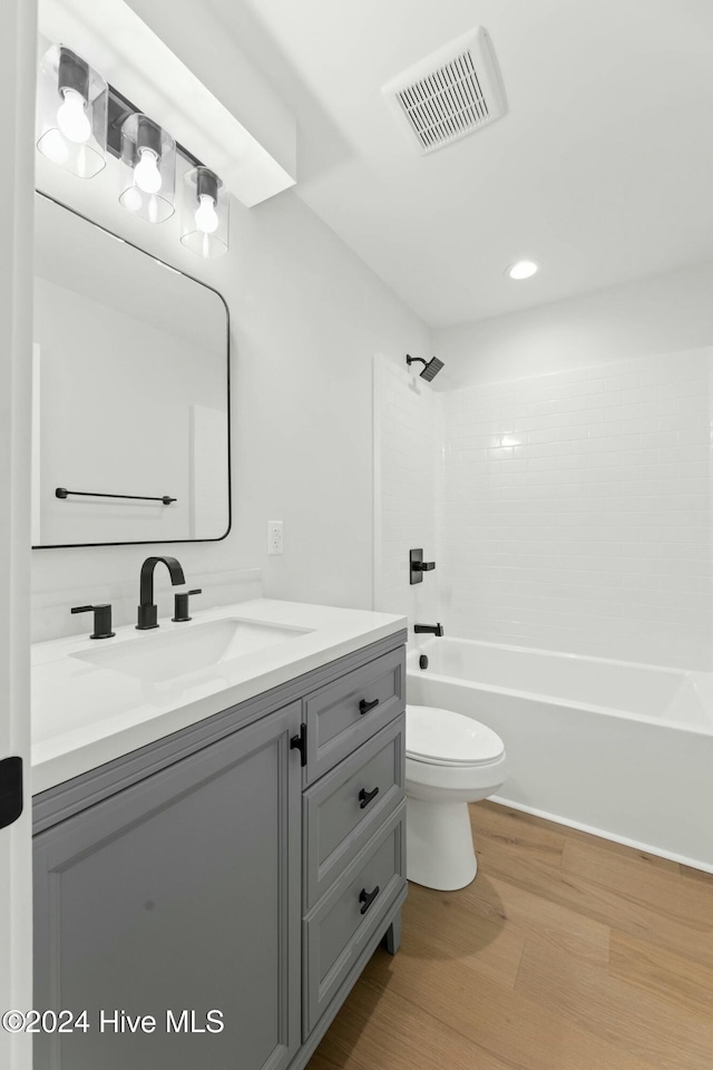 full bathroom featuring hardwood / wood-style flooring, vanity, toilet, and washtub / shower combination