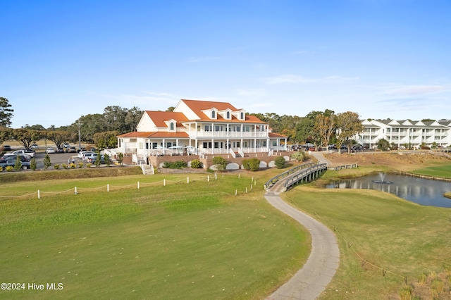 back of property with a lawn and a water view