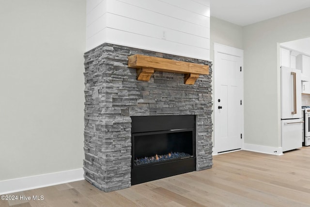 interior details featuring hardwood / wood-style flooring, a stone fireplace, and white appliances