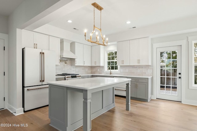 kitchen with dishwasher, stainless steel range with gas cooktop, wall chimney range hood, white cabinetry, and high end white refrigerator