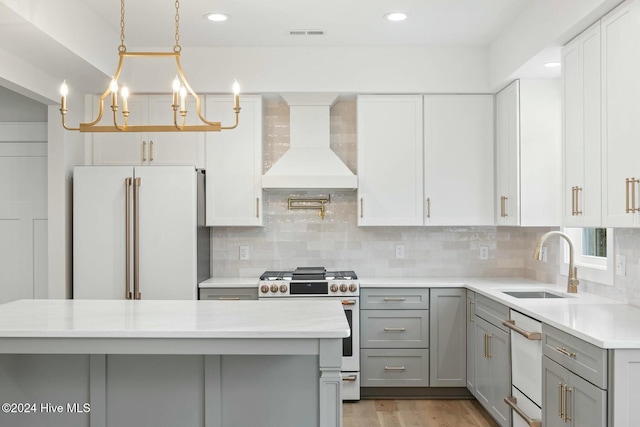 kitchen featuring pendant lighting, backsplash, premium range hood, white refrigerator, and stainless steel range