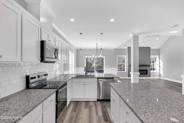 kitchen featuring backsplash, white cabinets, sink, stainless steel appliances, and decorative columns