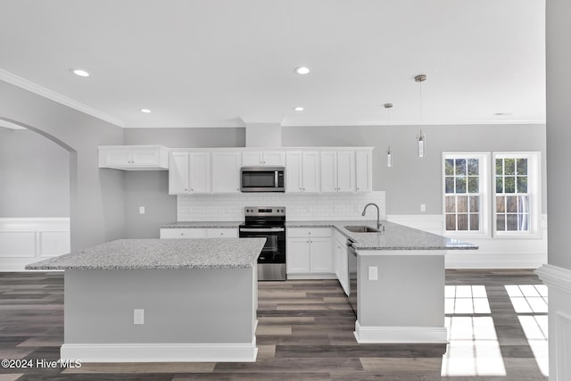 kitchen with pendant lighting, sink, light stone counters, white cabinetry, and stainless steel appliances