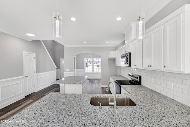 kitchen featuring pendant lighting, sink, a kitchen island, light stone counters, and stainless steel appliances