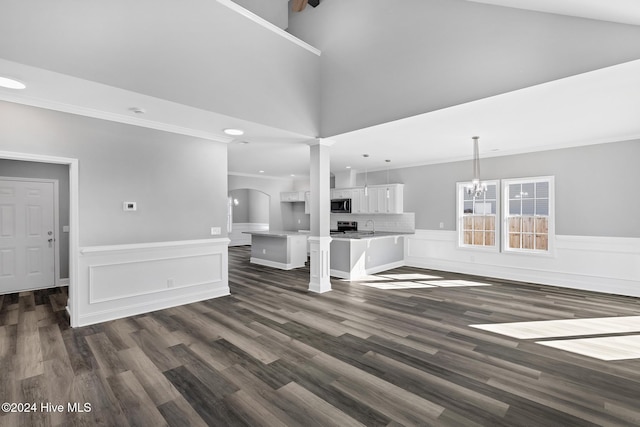 unfurnished living room with a high ceiling, dark hardwood / wood-style flooring, and ornamental molding