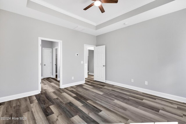 unfurnished bedroom featuring ceiling fan, dark hardwood / wood-style flooring, ornamental molding, and a tray ceiling