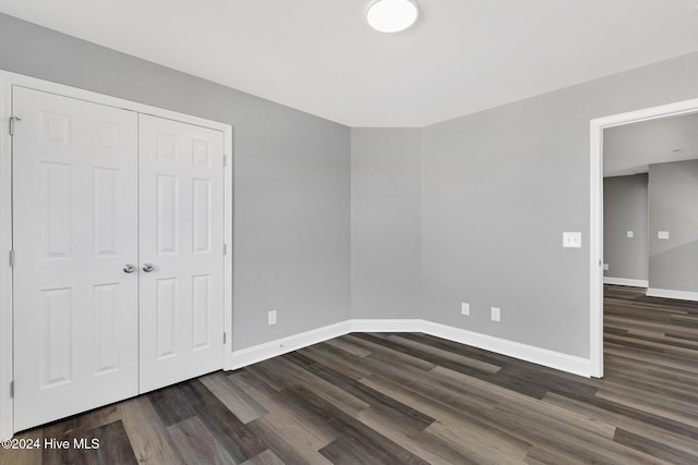 unfurnished bedroom with dark hardwood / wood-style floors and a closet