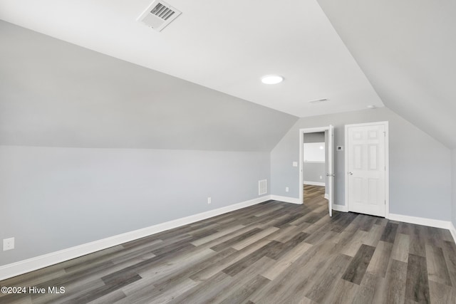 bonus room with dark wood-type flooring and vaulted ceiling