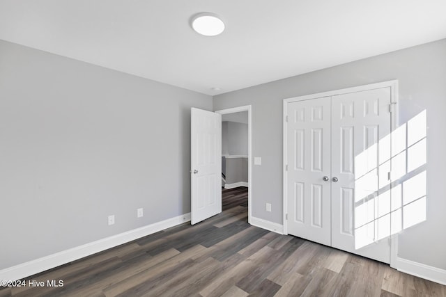 unfurnished bedroom featuring a closet and dark wood-type flooring