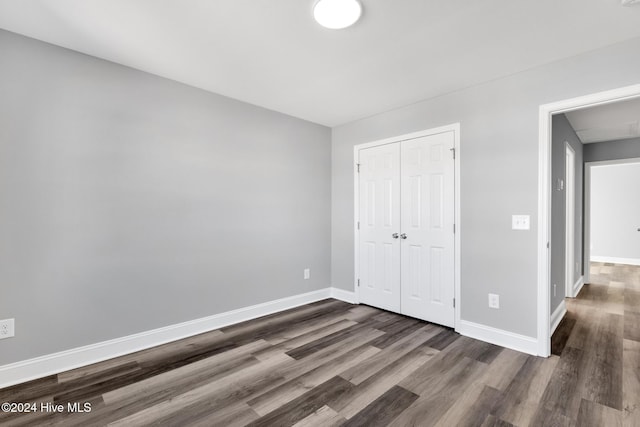 unfurnished bedroom with dark hardwood / wood-style flooring and a closet