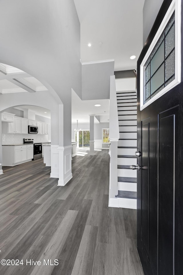 entryway with a high ceiling, dark wood-type flooring, and crown molding