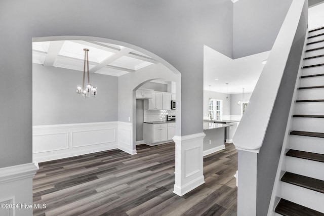 interior space with beam ceiling, dark hardwood / wood-style floors, coffered ceiling, and a notable chandelier