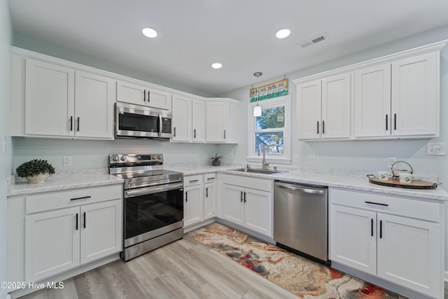 kitchen with white cabinets, visible vents, stainless steel appliances, and a sink