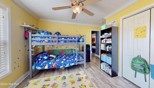 bedroom with a textured ceiling, ceiling fan, crown molding, hardwood / wood-style flooring, and a closet