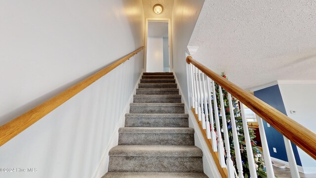 staircase featuring a textured ceiling and ornamental molding