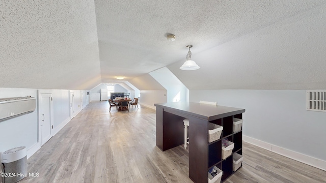 bonus room featuring light hardwood / wood-style floors, a textured ceiling, and vaulted ceiling