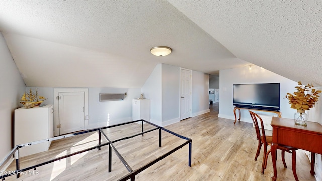 interior space with a textured ceiling, light wood-type flooring, and lofted ceiling