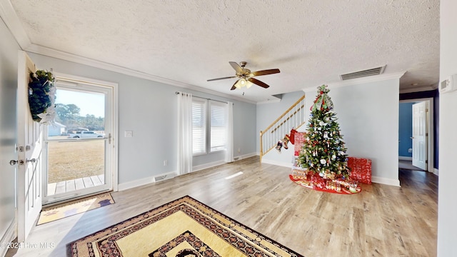 entrance foyer featuring a textured ceiling, light wood-type flooring, ceiling fan, and ornamental molding