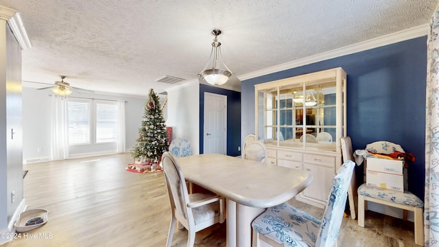 dining area featuring light wood-type flooring, a textured ceiling, ceiling fan, and crown molding