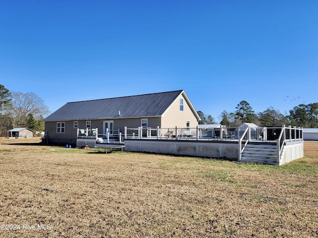 rear view of property featuring a lawn and a deck