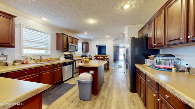 kitchen with crown molding, sink, a textured ceiling, appliances with stainless steel finishes, and light hardwood / wood-style floors