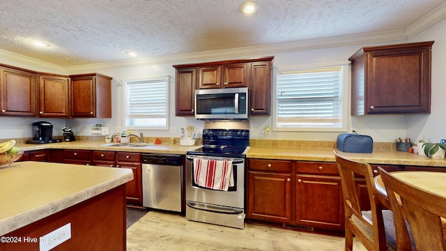 kitchen with sink, ornamental molding, a textured ceiling, and appliances with stainless steel finishes