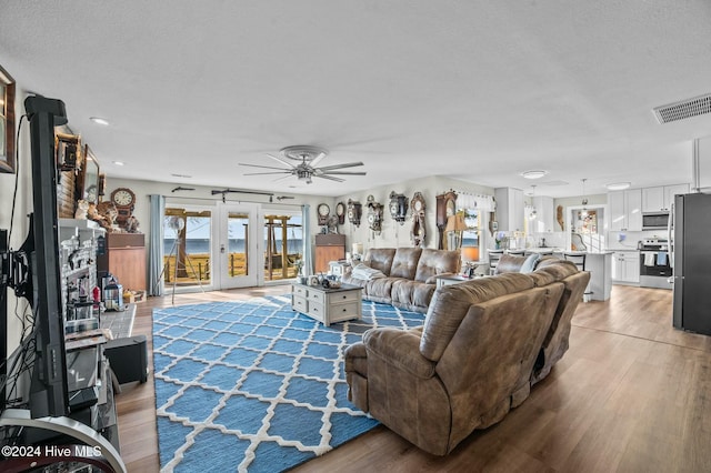 living room featuring ceiling fan, light hardwood / wood-style floors, and a textured ceiling