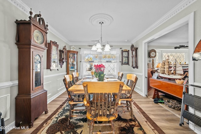 dining space featuring a notable chandelier, light hardwood / wood-style floors, and ornamental molding