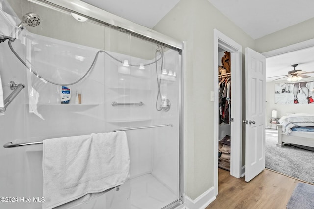 bathroom with ceiling fan, hardwood / wood-style floors, and a shower with shower door