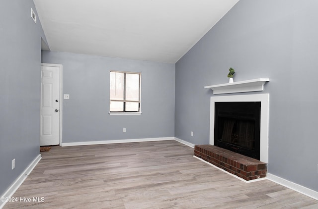 unfurnished living room with a fireplace, vaulted ceiling, and light hardwood / wood-style flooring