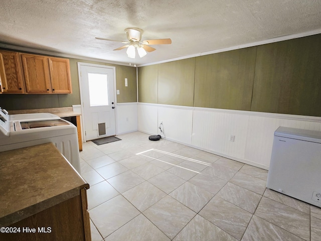 washroom featuring ceiling fan, a textured ceiling, wooden walls, washer and clothes dryer, and light tile patterned floors