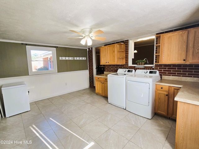 laundry area featuring ceiling fan, cabinets, brick wall, independent washer and dryer, and a textured ceiling