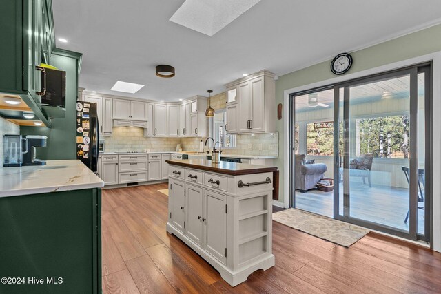 kitchen with a skylight, light wood-style floors, and green cabinetry