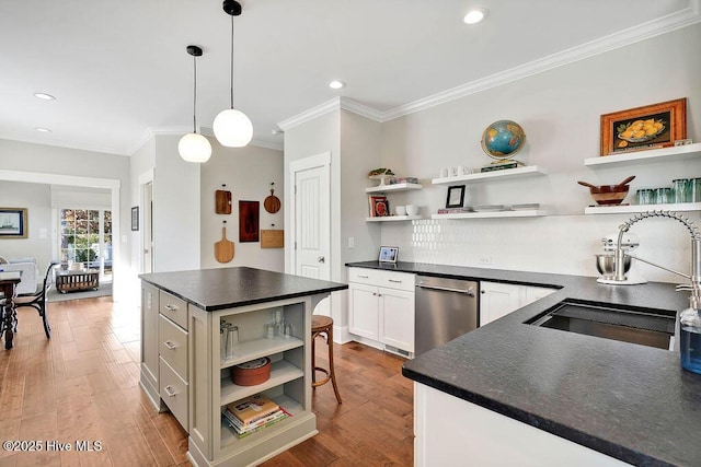 kitchen featuring white cabinetry, sink, a center island, hanging light fixtures, and light hardwood / wood-style floors