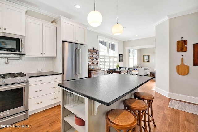 kitchen featuring a breakfast bar, white cabinetry, stainless steel appliances, and tasteful backsplash