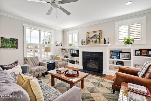 living room featuring ceiling fan, crown molding, light wood-type flooring, and a fireplace