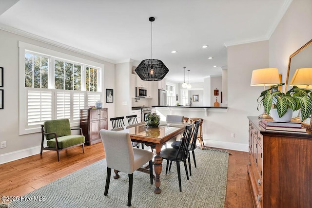 dining room with sink, ornamental molding, and light wood-type flooring