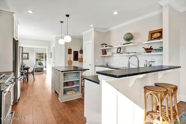 kitchen with stainless steel appliances, sink, decorative light fixtures, light hardwood / wood-style flooring, and white cabinets