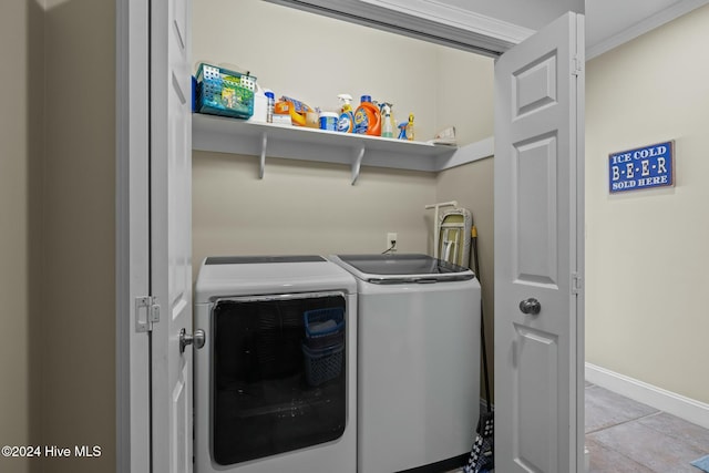 clothes washing area featuring washer and clothes dryer, light tile patterned floors, and crown molding