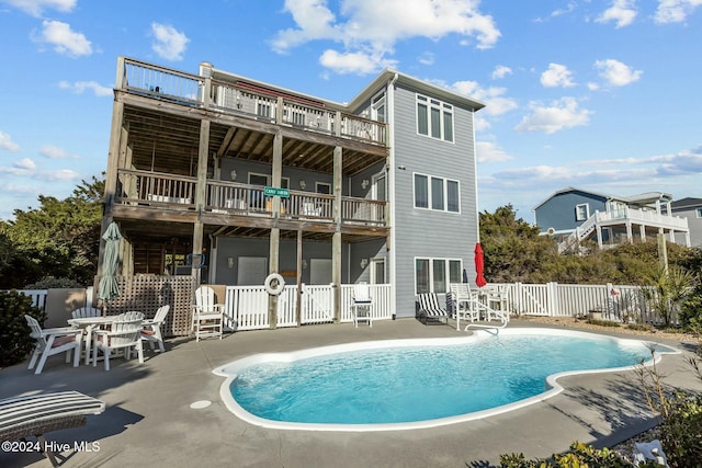 back of property with a fenced in pool, a balcony, and a patio