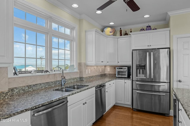 kitchen featuring white cabinets, appliances with stainless steel finishes, light stone counters, and sink