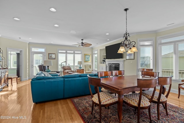 dining room featuring ceiling fan with notable chandelier, light hardwood / wood-style floors, ornamental molding, and built in features