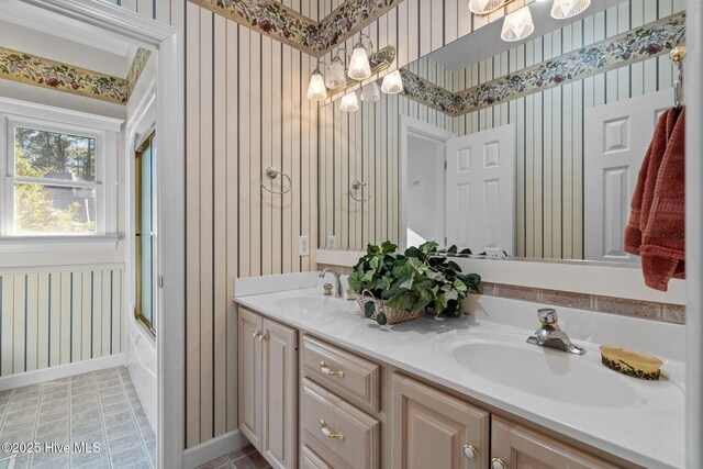 7 Brinyan Ct, Pinehurst, NC 28374 - bathroom featuring wallpapered walls, double vanity, a chandelier, baseboards, and bath / shower combo with glass door