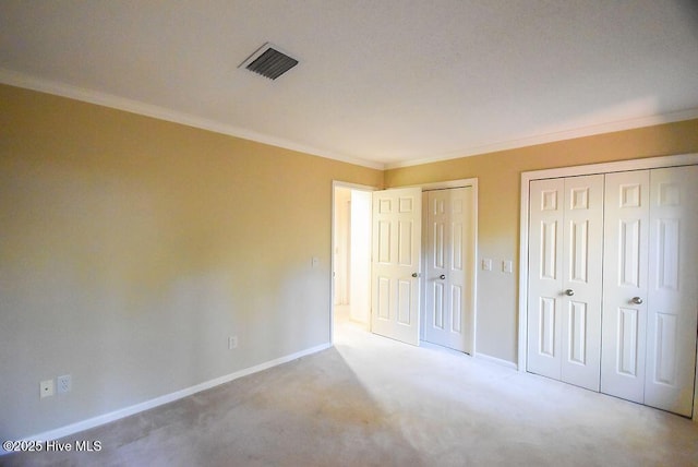 unfurnished bedroom featuring light colored carpet, two closets, and ornamental molding