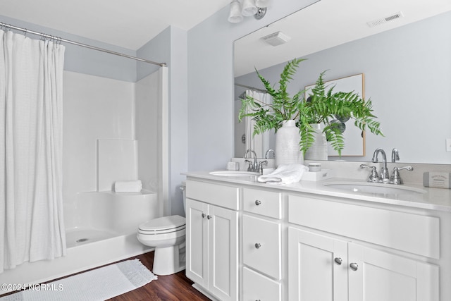 bathroom with a sink, visible vents, wood finished floors, and double vanity