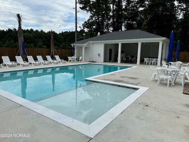 community pool with an outbuilding, a patio, and fence