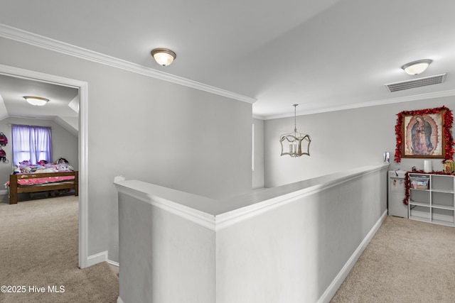 hall with ornamental molding, lofted ceiling, light colored carpet, and an inviting chandelier